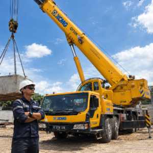 Operator profesional mengawasi armada sewa mobil crane 50 ton yang sedang beroperasi mengangkat material berat di area proyek Jakarta dan Tangerang.